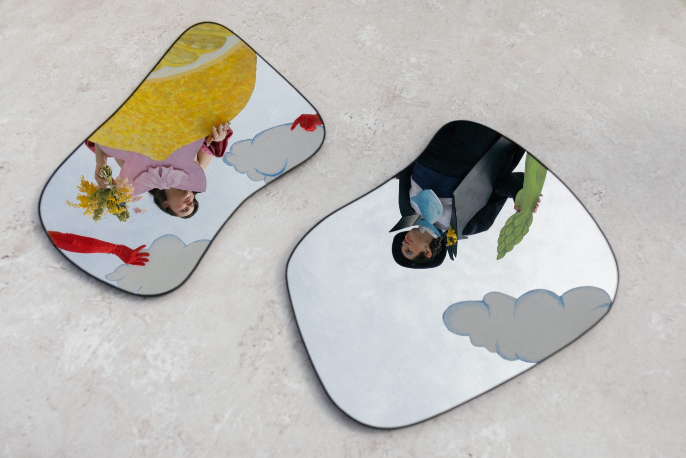 Organic-shaped mirrors on the ground, reflecting two women in 2D costumes